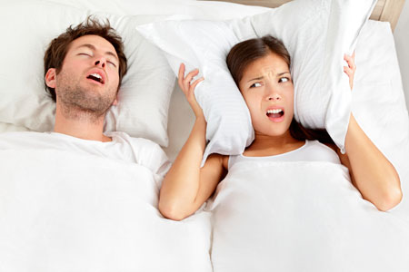 A man and woman in bed with pillows on their heads.