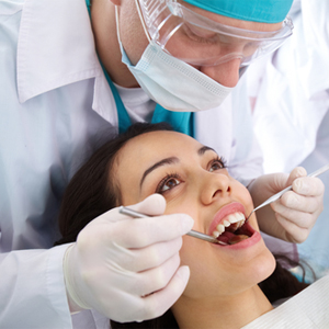 A dentist is examining the teeth of a patient.