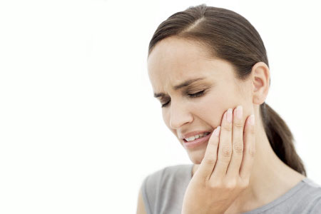 A woman holding her face in pain with an aching tooth.