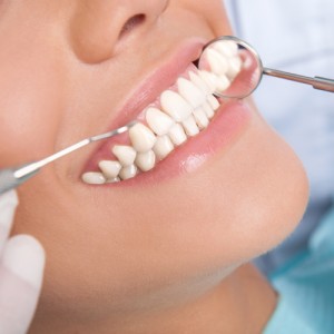 A woman is getting her teeth cleaned by dentist.